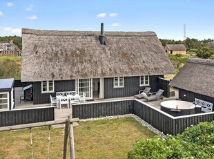 En stråtægtdrøm med spabad og et skønt terrassemiljø