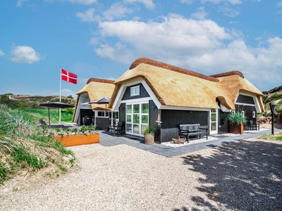 Stråtækt sommerhus beliggende idyllisk placeret i Henne Strands klitlandskab.