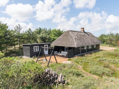 Charmerende stråtækt feriehus beliggende på en ugeneret, lyngklædt grund.