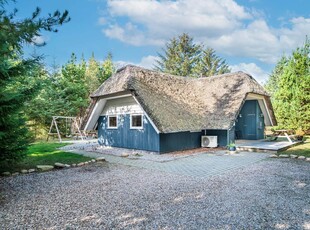 Pragtfuld kvalitetsferiehus beliggende på en dejlig, stor naturgrund med træer og græs.