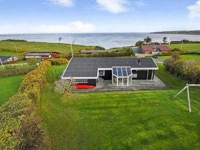 Dette hyggelige sommerhus med tilhørende anneks ligger på Gyvelvej 30 i Gjelleroddes kuperede landskab. Stranden ligger bare 130 meter væk, og fra stuen og terrassen har I det flotteste panoramavue over Limfjorden.